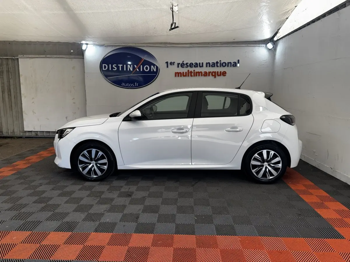 Profil côté gauche d'une Peugeot 208 blanche de 2020, avec jantes alliage et rétroviseurs noirs dans un showroom.