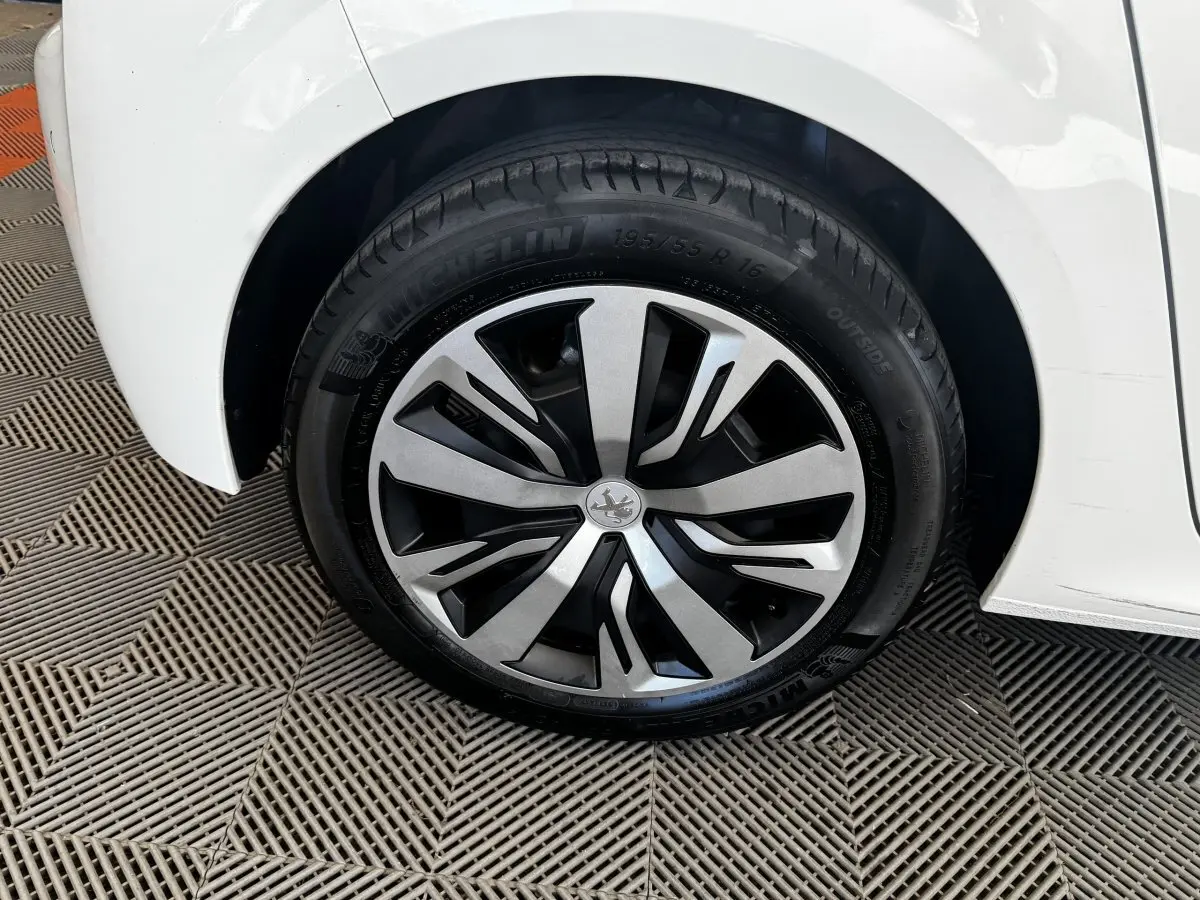 Gros plan sur la roue arrière droite de la Peugeot 208 blanche, avec jante alliage au design moderne.
