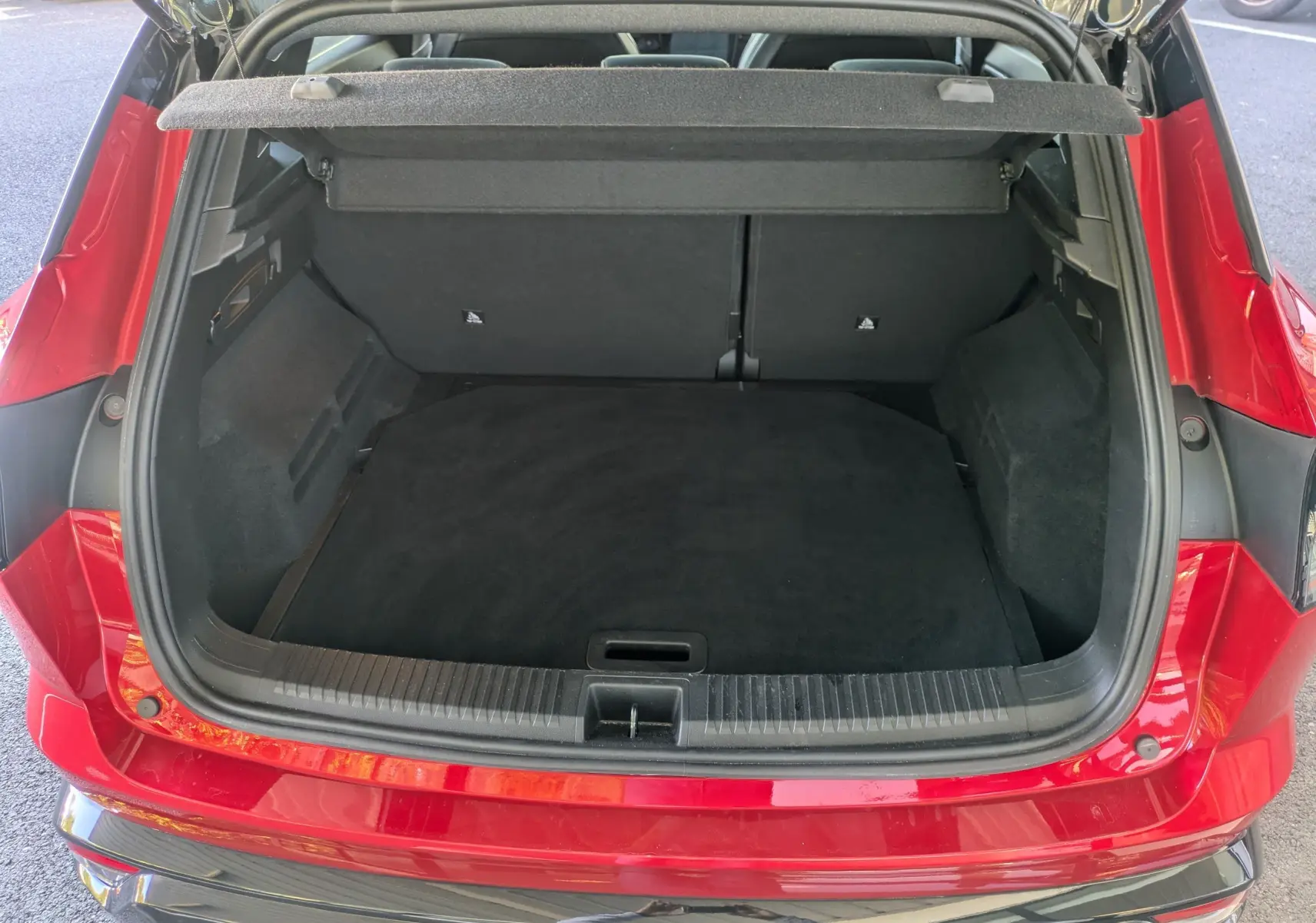 Coffre ouvert vu de l'arrière d'un Renault Austral 2025 Rouge Flamme, montrant un espace de chargement propre et spacieux.