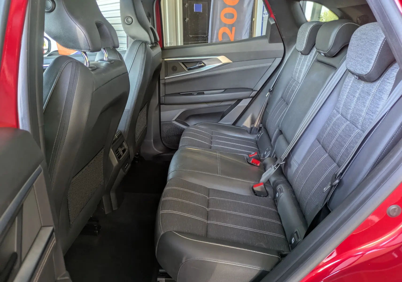Vue intérieure côté droit des sièges arrière du Renault Austral Rouge Flamme avec sellerie mixte tissu et cuir.