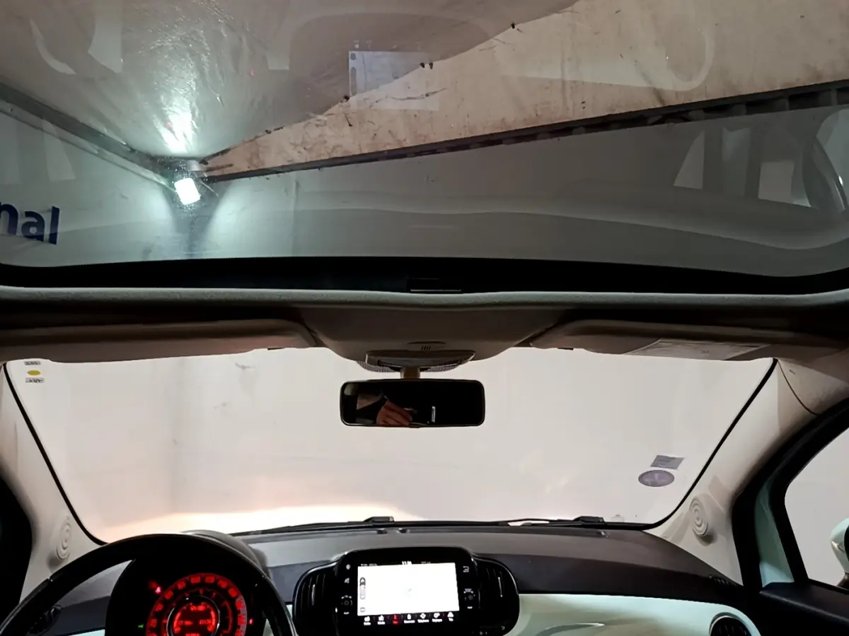 Vue intérieure avant du tableau de bord et volant cuir noir de la FIAT 500 Lounge 2019 avec toit panoramique.