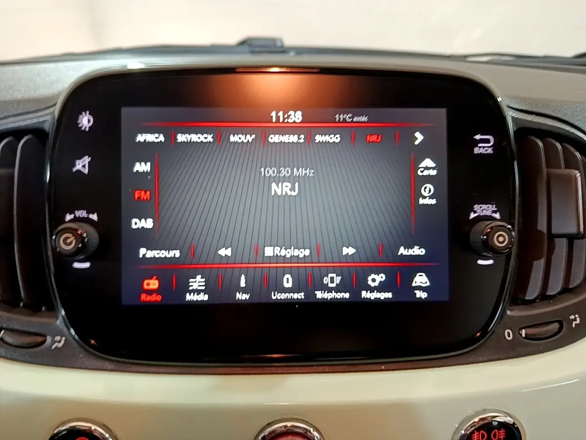 Écran tactile central affichant la radio NRJ dans l'habitacle beige clair d'une Fiat 500 Lounge 2019.