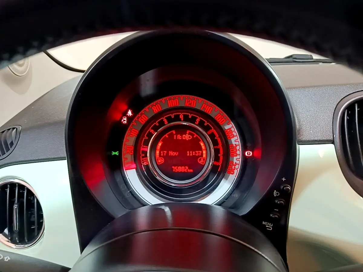 Vue rapprochée du tableau de bord numérique rouge de la Fiat 500 verte, affichant la vitesse et le kilométrage.