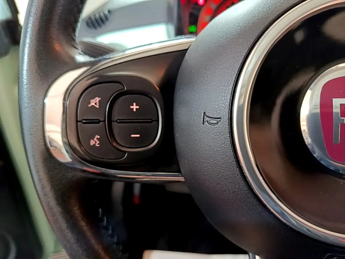 Gros plan sur le volant cuir multifonctions de la FIAT 500 Lounge 2019, boutons de contrôle audio visibles.