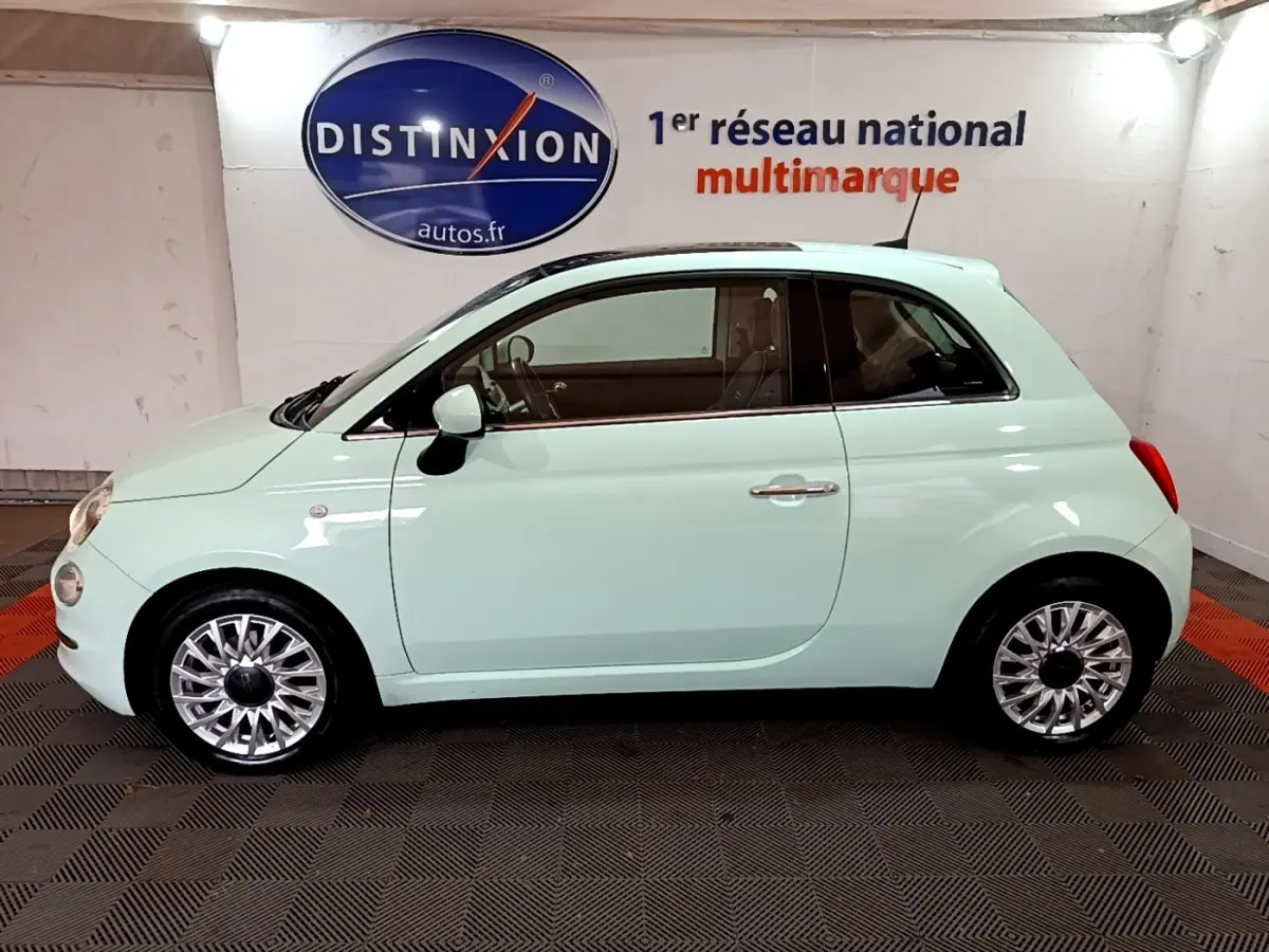 Profil côté gauche d'une FIAT 500 Lounge 2019 vert clair avec jantes alliage et toit noir en intérieur showroom.