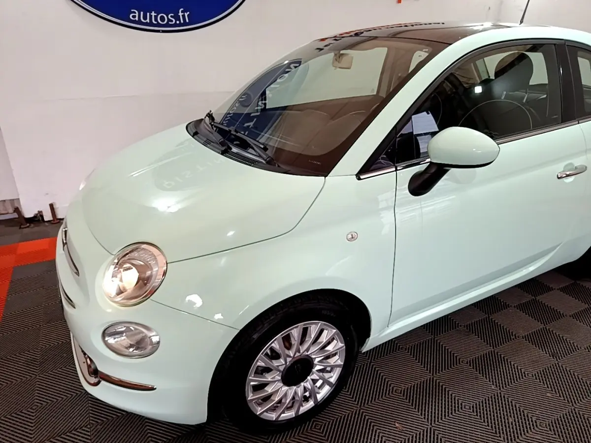 Vue 3/4 avant droit d'une FIAT 500 Lounge 2019 vert clair avec toit noir et jantes alliage multibranches.