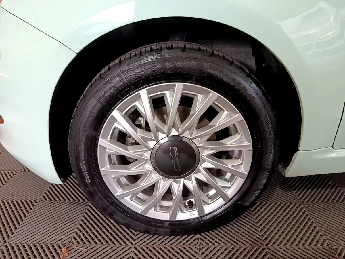 Gros plan sur la roue avant gauche argentée d'une FIAT 500 verte 2019 avec jante à rayons fins.