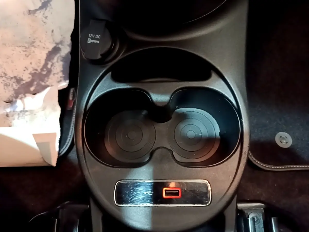 Vue rapprochée de la console centrale noire de la Fiat 500 Lounge 2019 avec prise 12V et porte-gobelets.