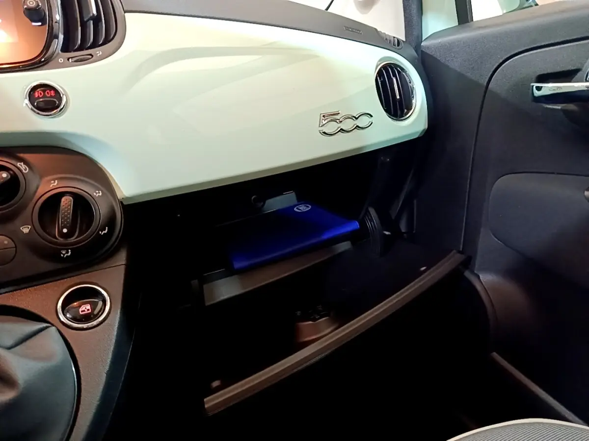 Intérieur de la Fiat 500 2019, tableau de bord vert clair avec boîte à gants ouverte côté passager.