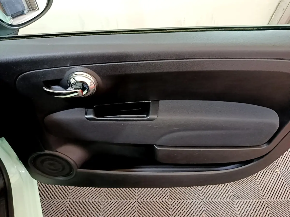 Gros plan sur la porte intérieure côté gauche de la Fiat 500 Lounge 2019 avec poignée chromée et panneau noir.