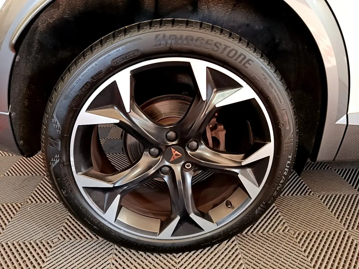 Gros plan sur la jante alliage noire et argentée avec logo CUPRA, montée sur pneu Bridgestone, partie avant droite visible.