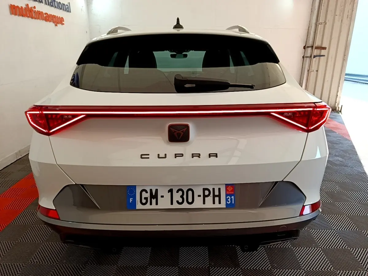 Vue arrière d'une CUPRA Formentor blanche avec feux LED reliés par une barre lumineuse rouge.