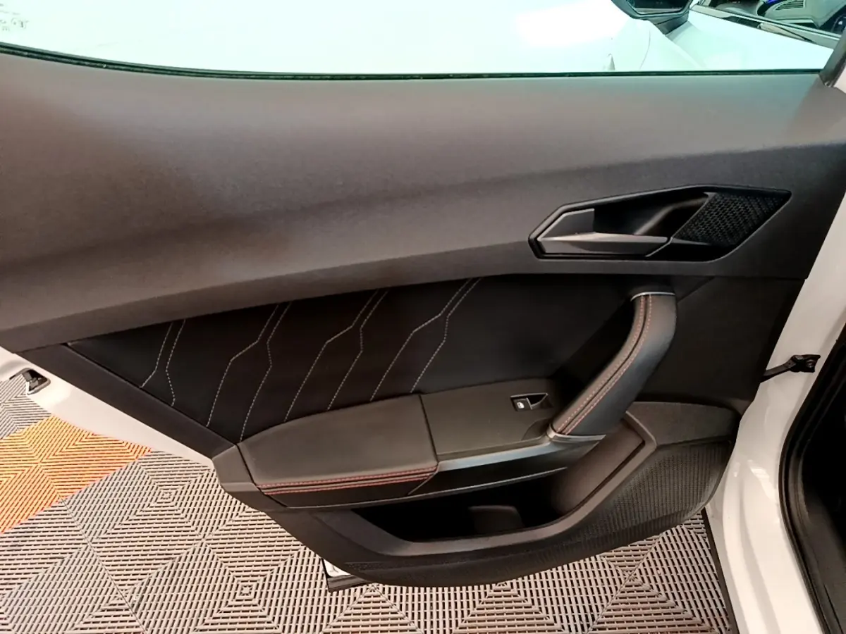 Gros plan sur la porte avant droite blanche du CUPRA Formentor 2023, avec garniture noire et surpiqûres rouges.