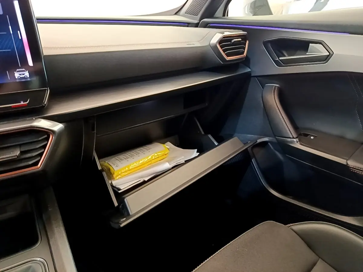 Intérieur noir et beige du CUPRA Formentor 2023, vue côté passager avec boîte à gants ouverte et éclairage d'ambiance violet.