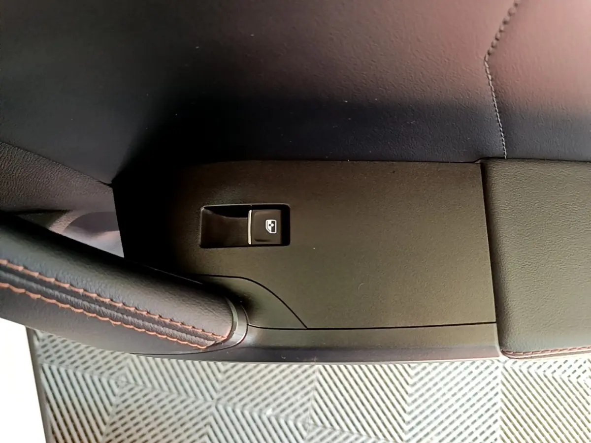 Détail de la commande de lève-vitre côté conducteur sur panneau noir avec surpiqûres rouges dans l’habitacle d’un CUPRA Formentor.
