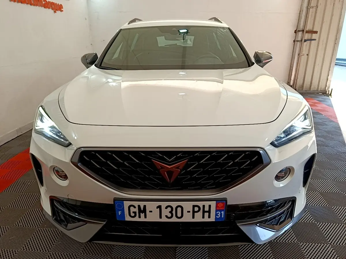 Vue avant d'un CUPRA Formentor blanc avec calandre noire et logo orange, phares LED allumés en intérieur.