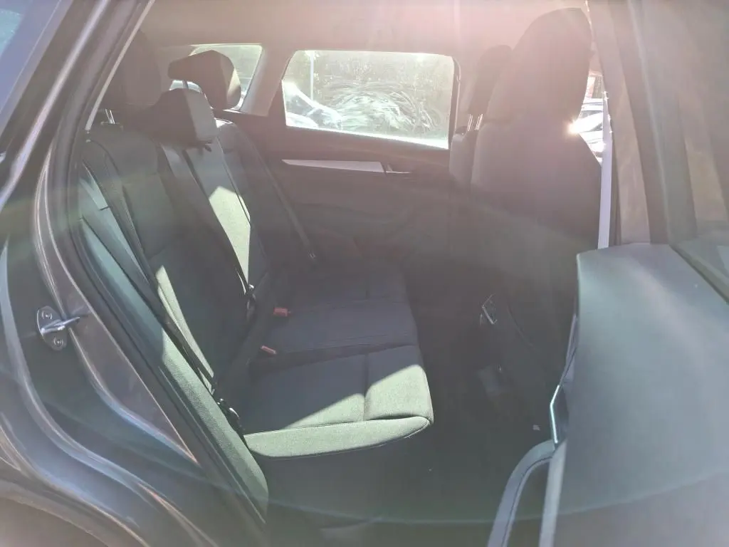 Vue intérieure côté droit des sièges arrière noirs du Skoda Karoq gris 2023 avec ceintures visibles et lumière naturelle.