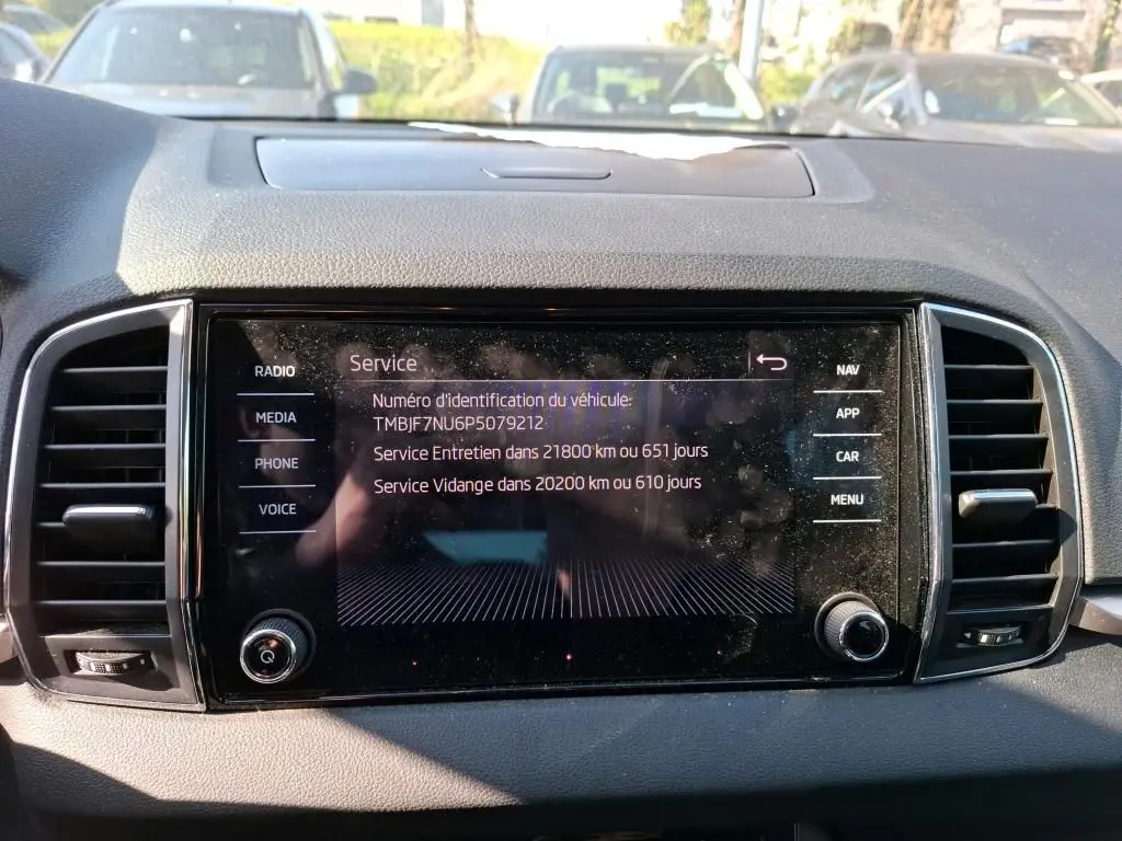 Écran tactile central du tableau de bord d'une Skoda Karoq 2.0 TDI gris, affichant les informations de service.