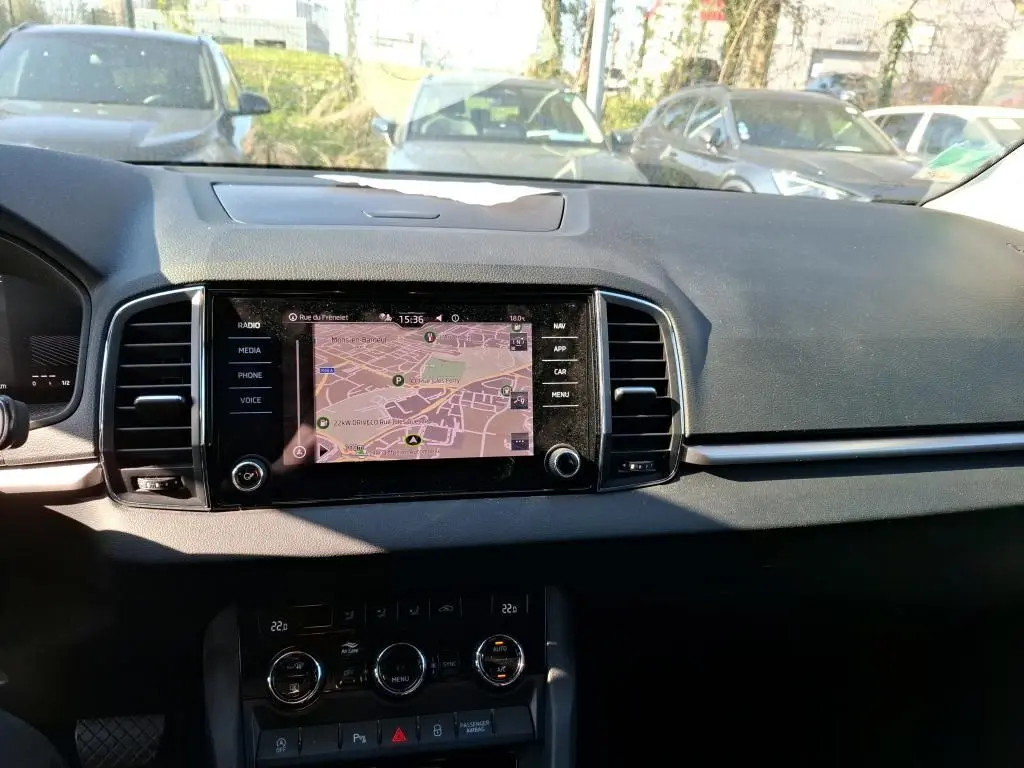 Vue intérieure du tableau de bord du Skoda Karoq gris 2023, avec écran tactile multimédia affichant la navigation.