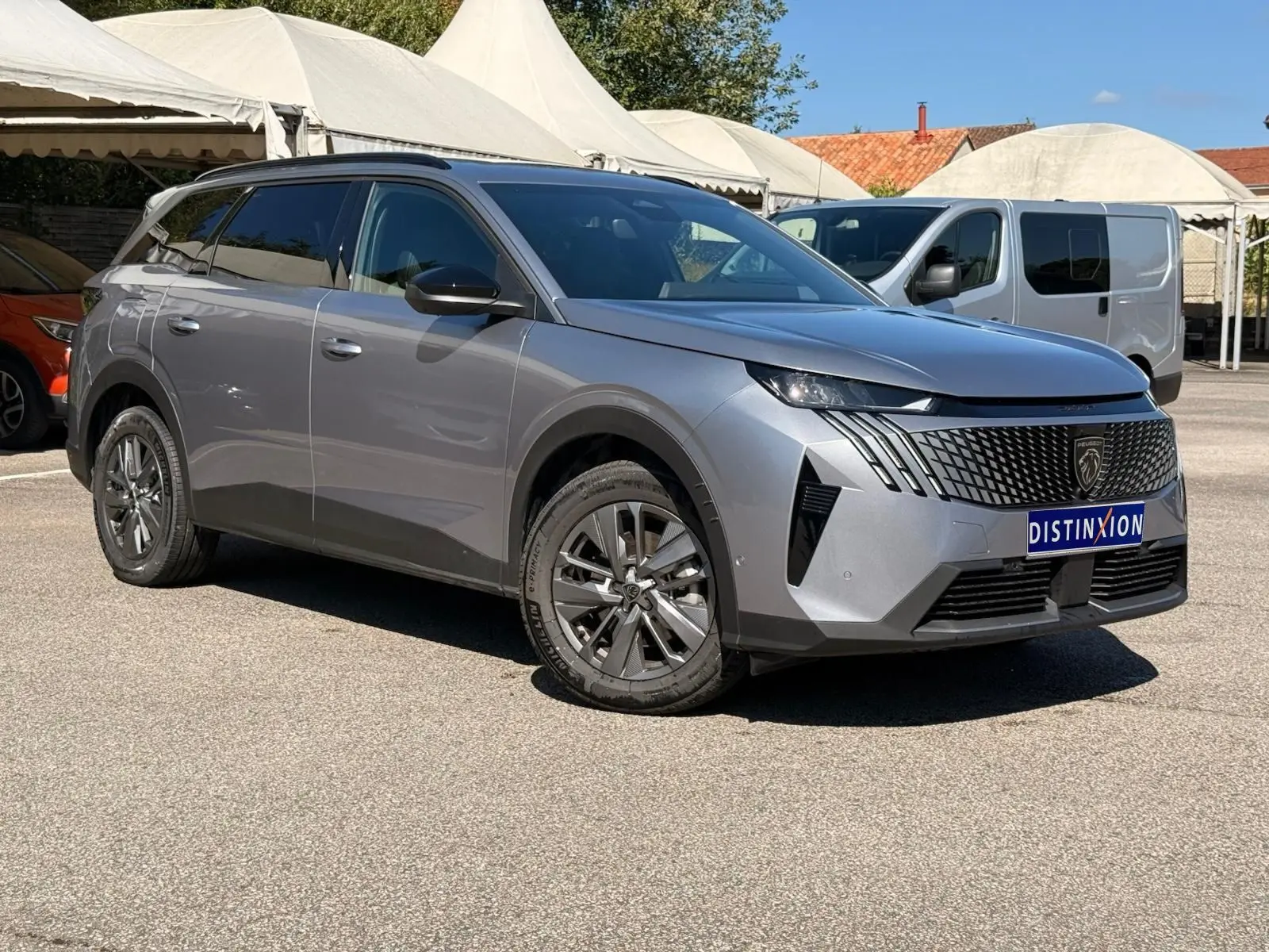 Peugeot 5008 gris Artense vue 3/4 avant droit, SUV hybride avec calandre noire et jantes alliage distinctives.
