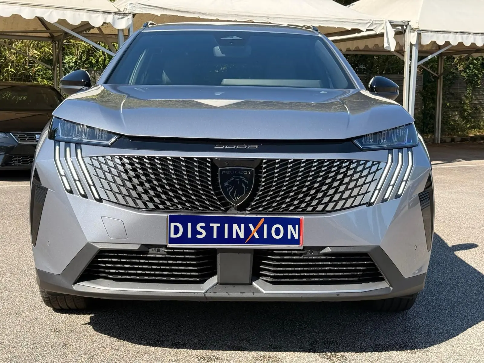 Vue frontale d'un Peugeot 5008 gris Artense avec calandre distinctive et feux LED en griffes verticales.