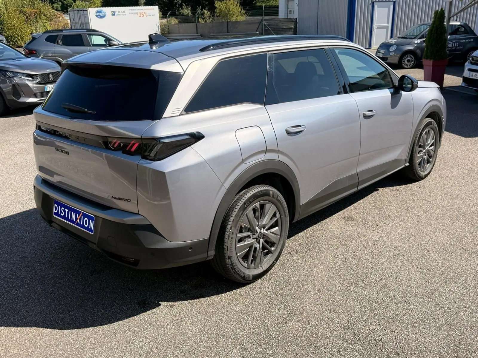 Vue 3/4 arrière droite d’un Peugeot 5008 gris Artense hybride 2025 avec vitres teintées et jantes alliage.