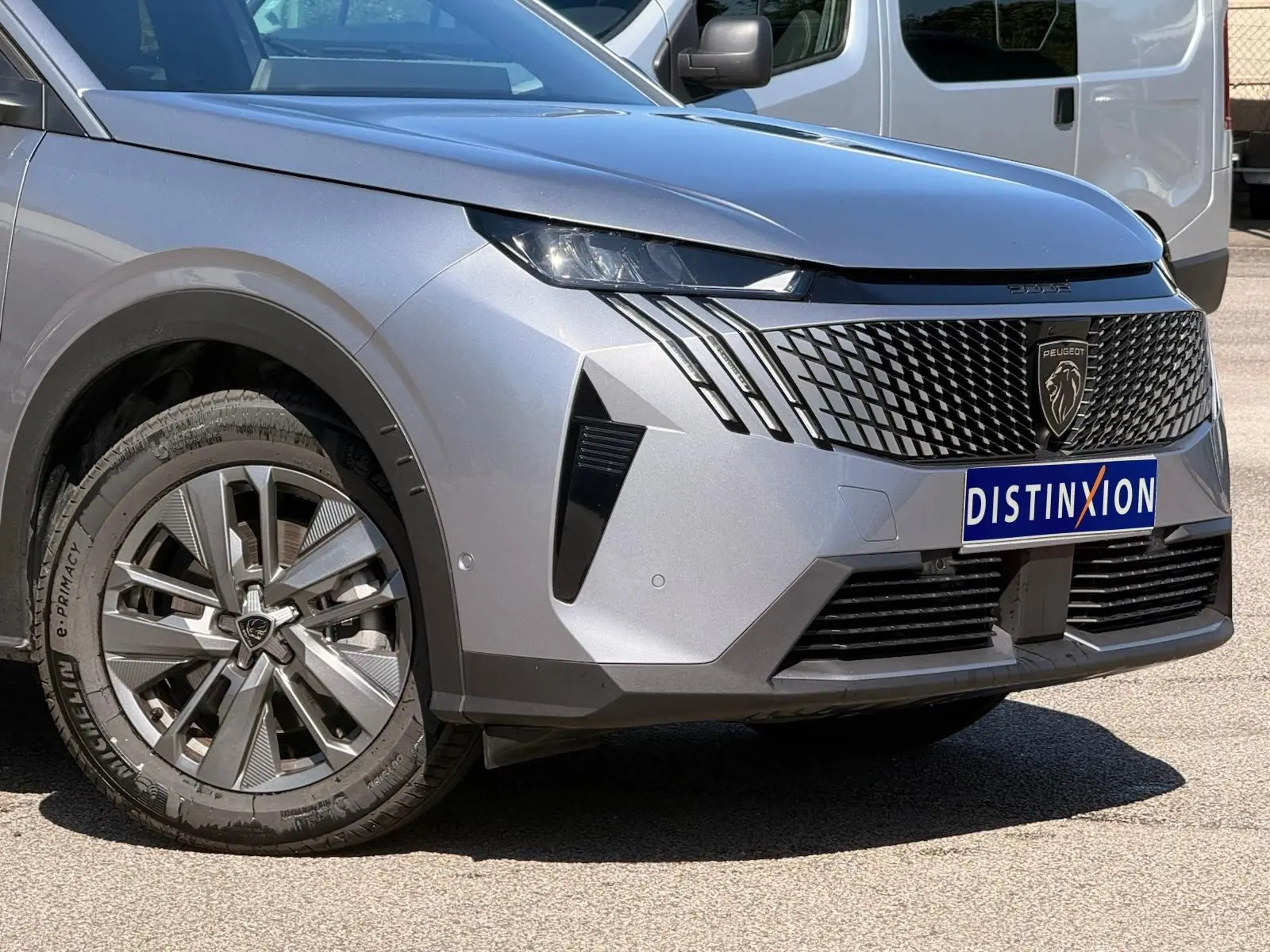 Vue 3/4 avant gauche du Peugeot 5008 2025 gris Artense avec calandre noire et phares LED distinctifs.