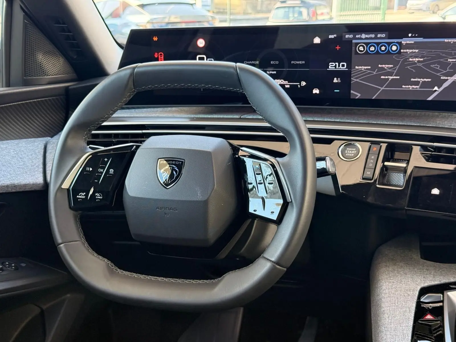 Vue intérieure centrée sur le volant cuir du Peugeot 5008 2025, avec tableau de bord numérique et écran tactile intégré.