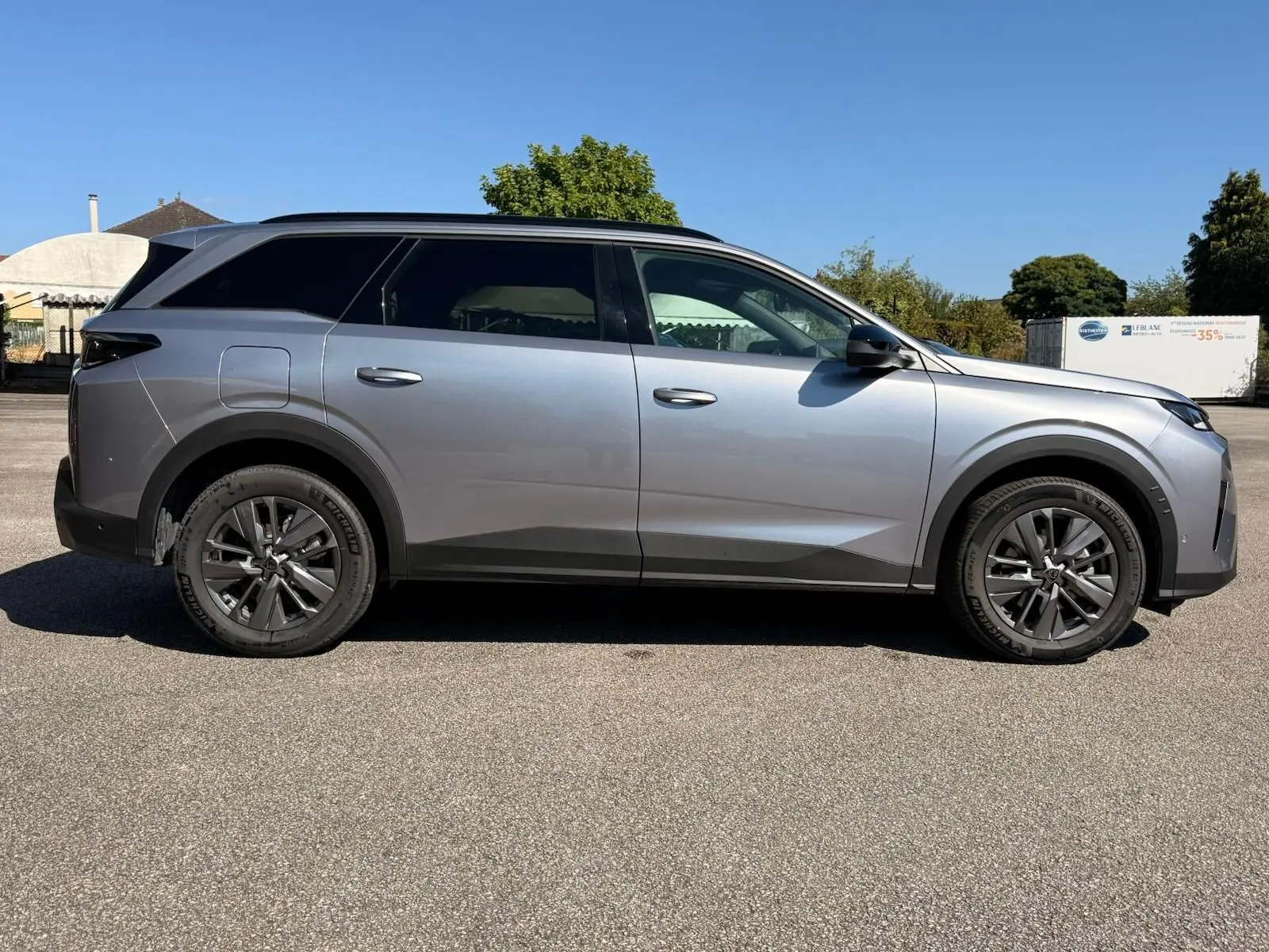 Peugeot 5008 gris Artense vue de profil côté gauche, SUV hybride 2025 avec jantes alliage foncé et toit noir.
