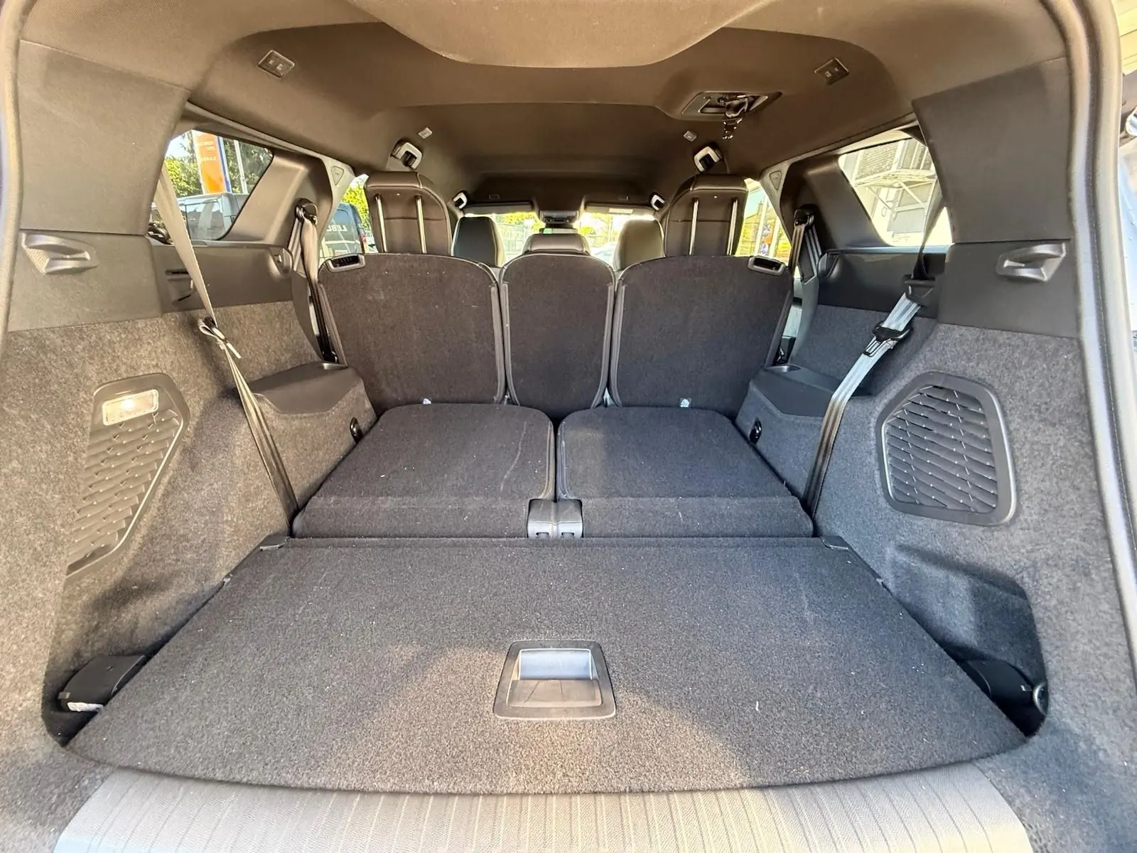 Vue intérieure arrière du coffre du Peugeot 5008 gris Artense avec sièges arrière rabattus, montrant un espace de chargement plat.