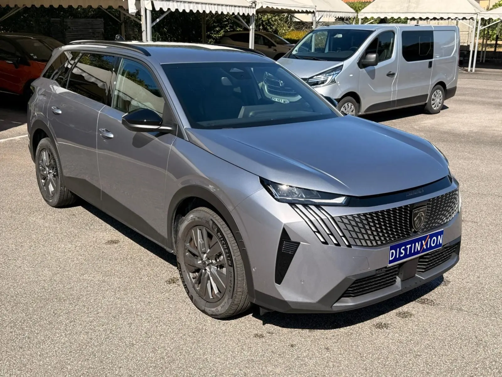 Peugeot 5008 gris Artense en 3/4 avant droit, mettant en valeur sa calandre distinctive et ses feux LED fins.