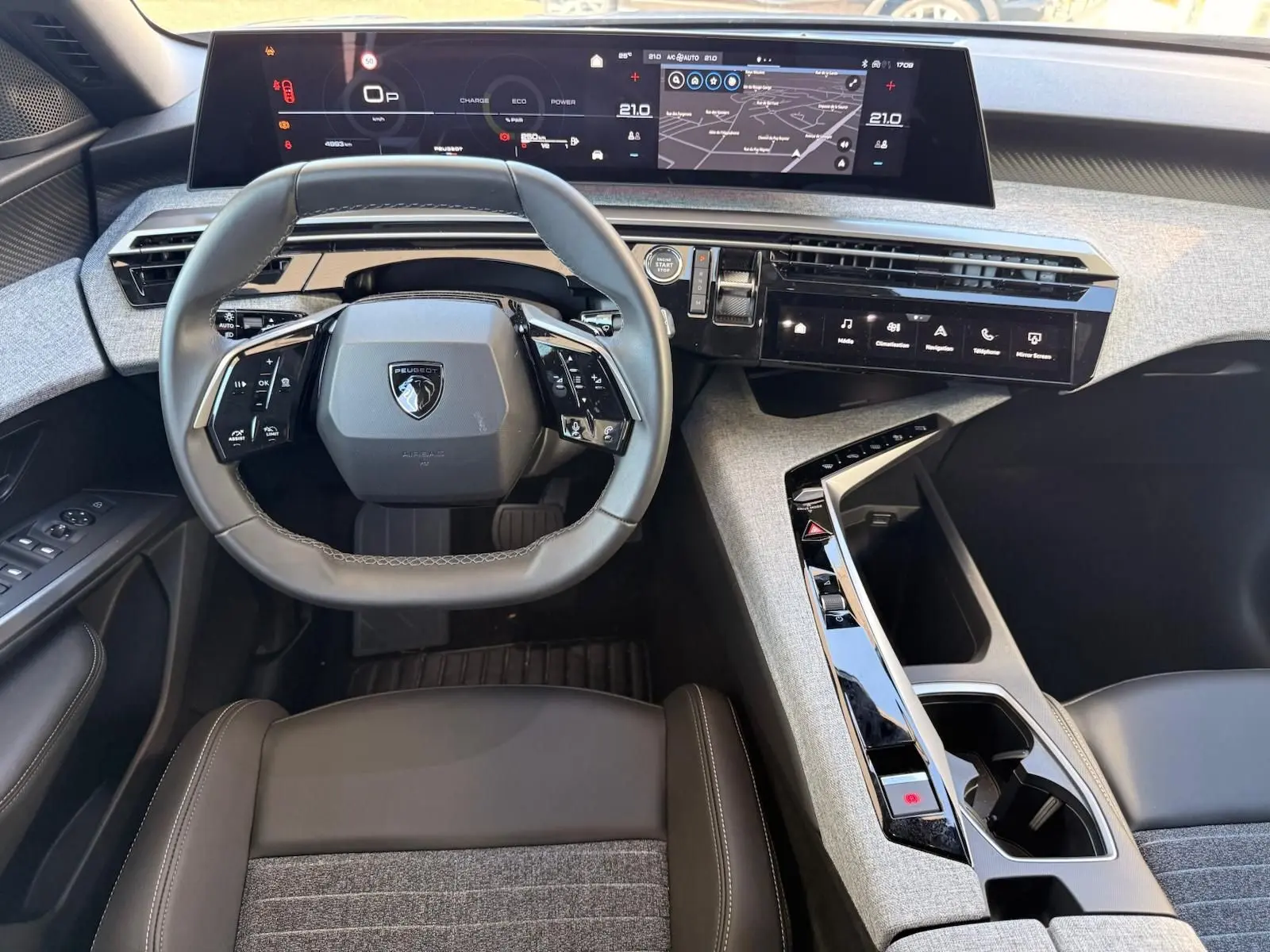 Vue intérieure frontale du poste de conduite du Peugeot 5008 gris Artense 2025, avec tableau de bord numérique et volant compact multifonction.