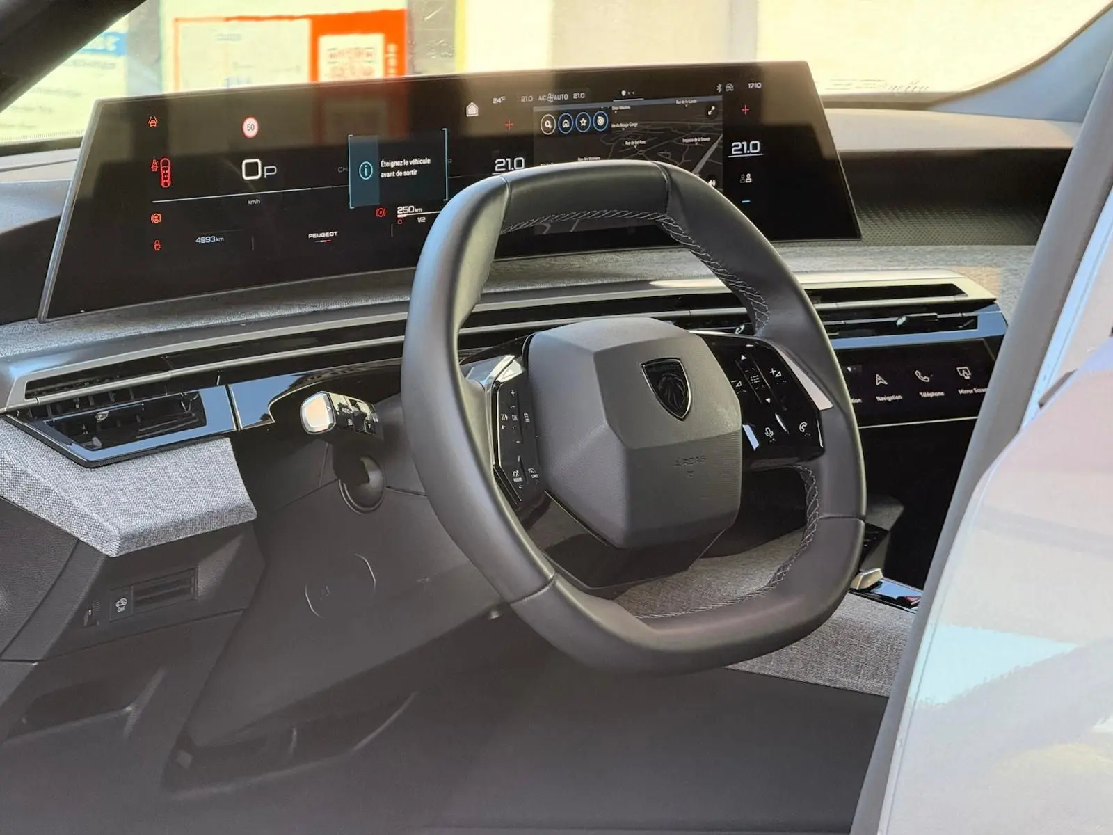 Vue intérieure du tableau de bord et volant du Peugeot 5008 gris Artense, avec écran numérique panoramique et commandes tactiles intégrées.