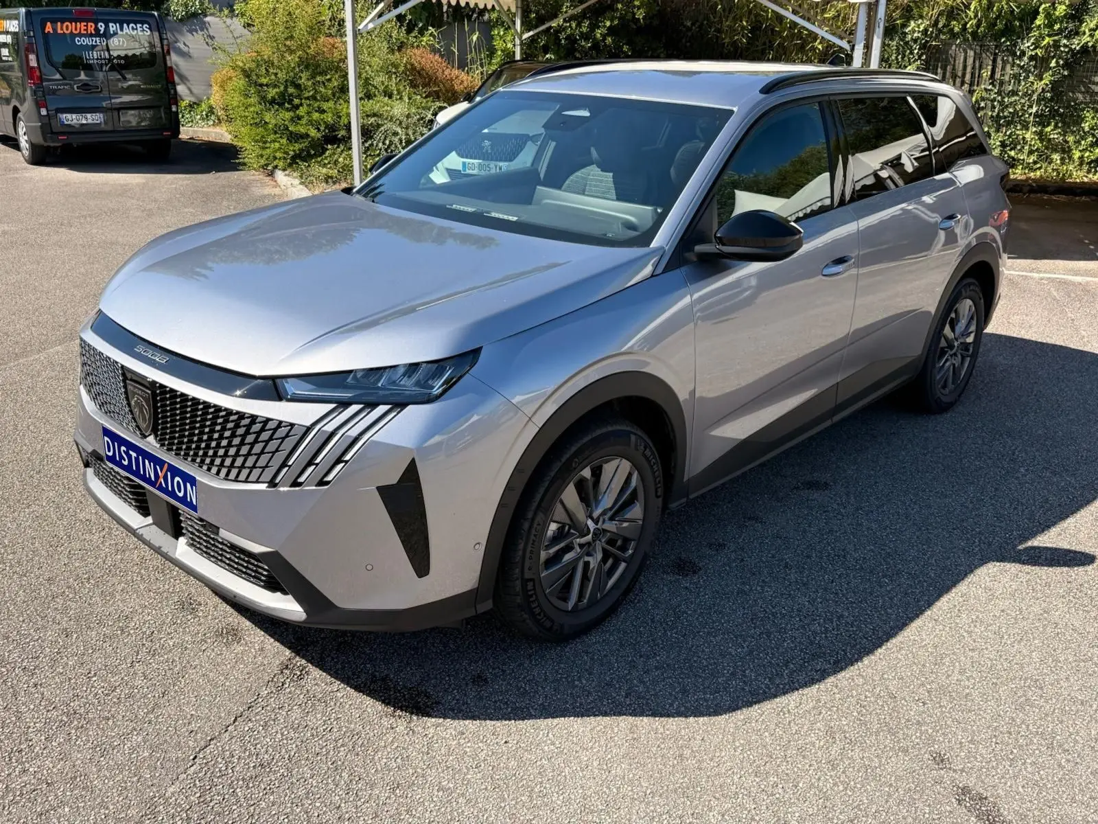 Peugeot 5008 gris Artense en 3/4 avant droit, mettant en valeur sa calandre distinctive et ses phares LED fins.