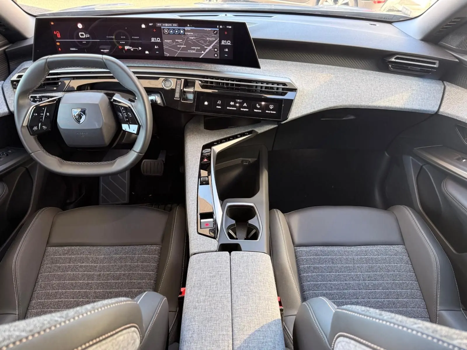 Vue intérieure avant du Peugeot 5008 2025, tableau de bord moderne avec écran digital large et sellerie gris foncé.