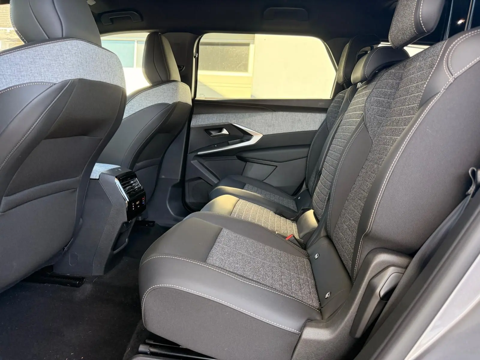 Vue intérieure côté droit des sièges arrière du Peugeot 5008 2025 gris Artense avec sellerie tissu et cuir bicolore.