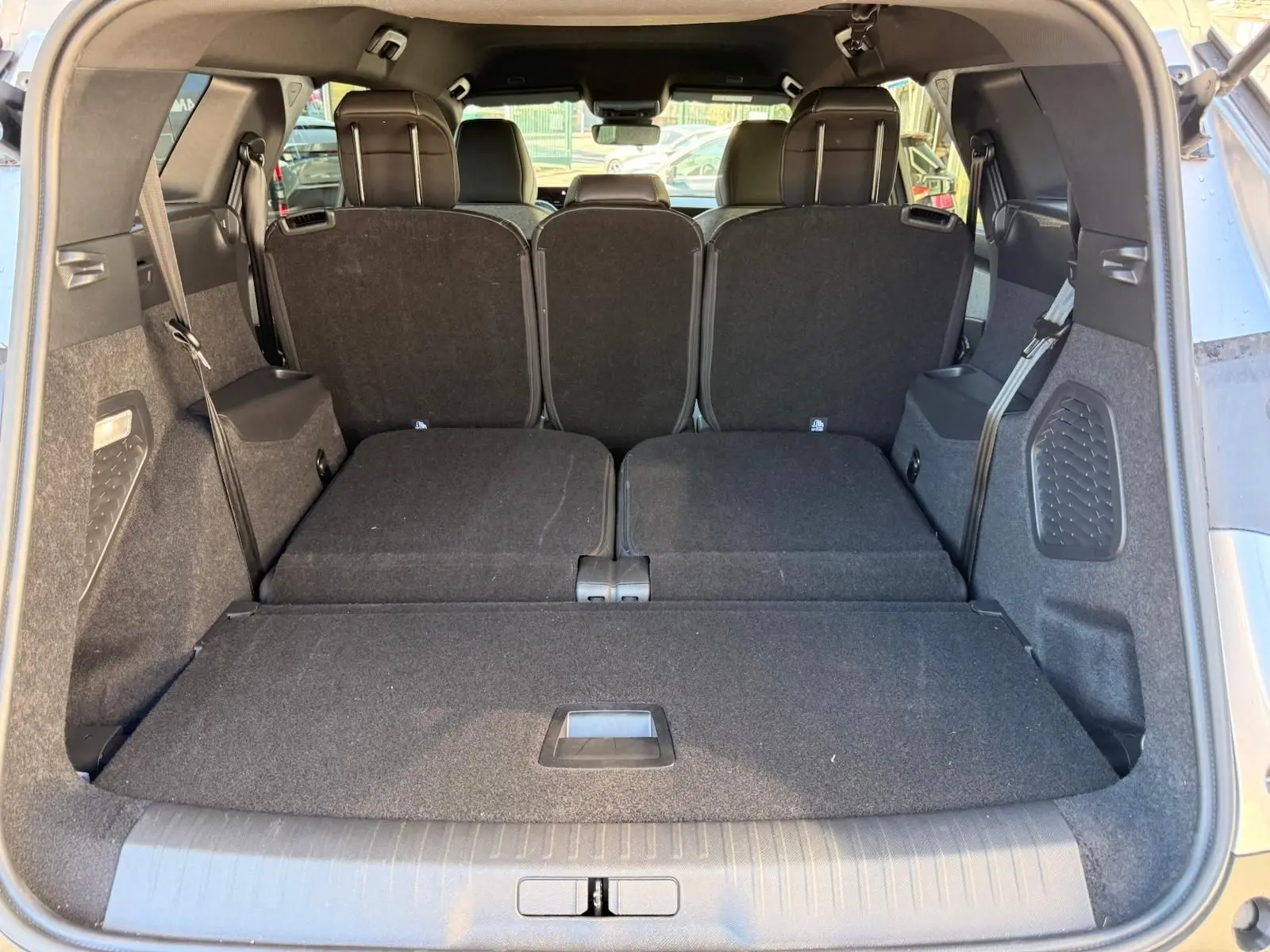 Vue arrière du coffre du Peugeot 5008 gris Artense 2025 avec sièges arrière partiellement rabattus et espace de chargement étendu.
