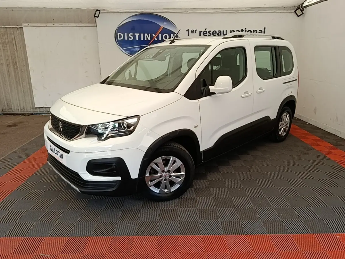 Peugeot Rifter blanc en 3/4 avant droit, avec jantes alliage et protections noires sur bas de caisse.