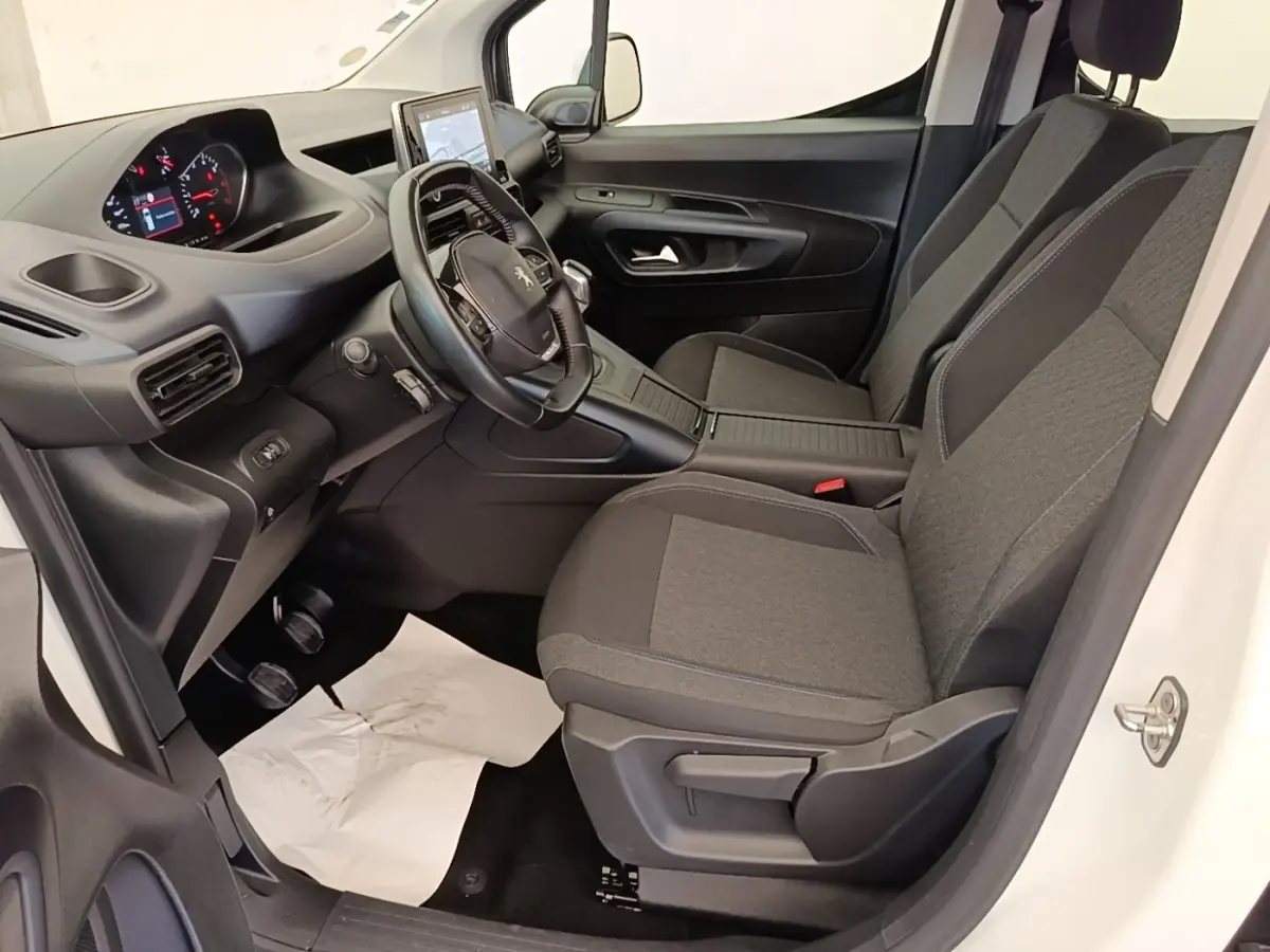 Vue intérieure côté conducteur du Peugeot Rifter blanc 2020, avec volant cuir multifonctions et sièges tissu gris.