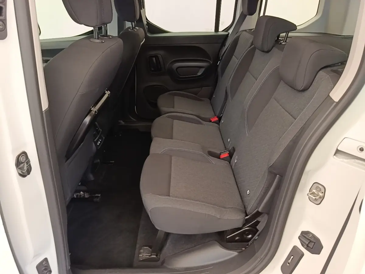 Vue intérieure côté droit sur la banquette arrière grise du Peugeot Rifter blanc, avec porte ouverte.