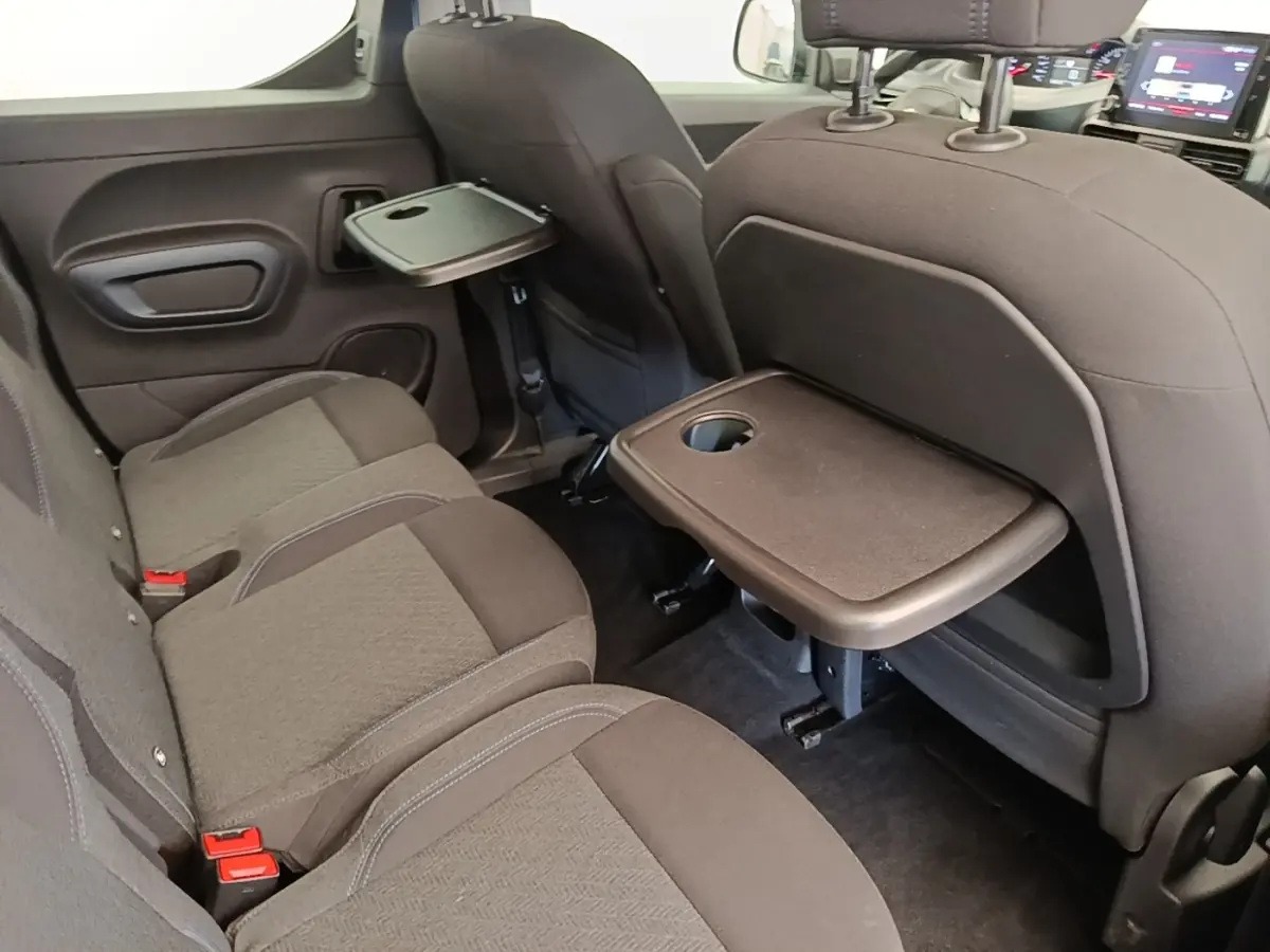Vue intérieure arrière du Peugeot Rifter 2020 avec banquette 3 places noire et tablettes rabattables sur les dossiers avant.
