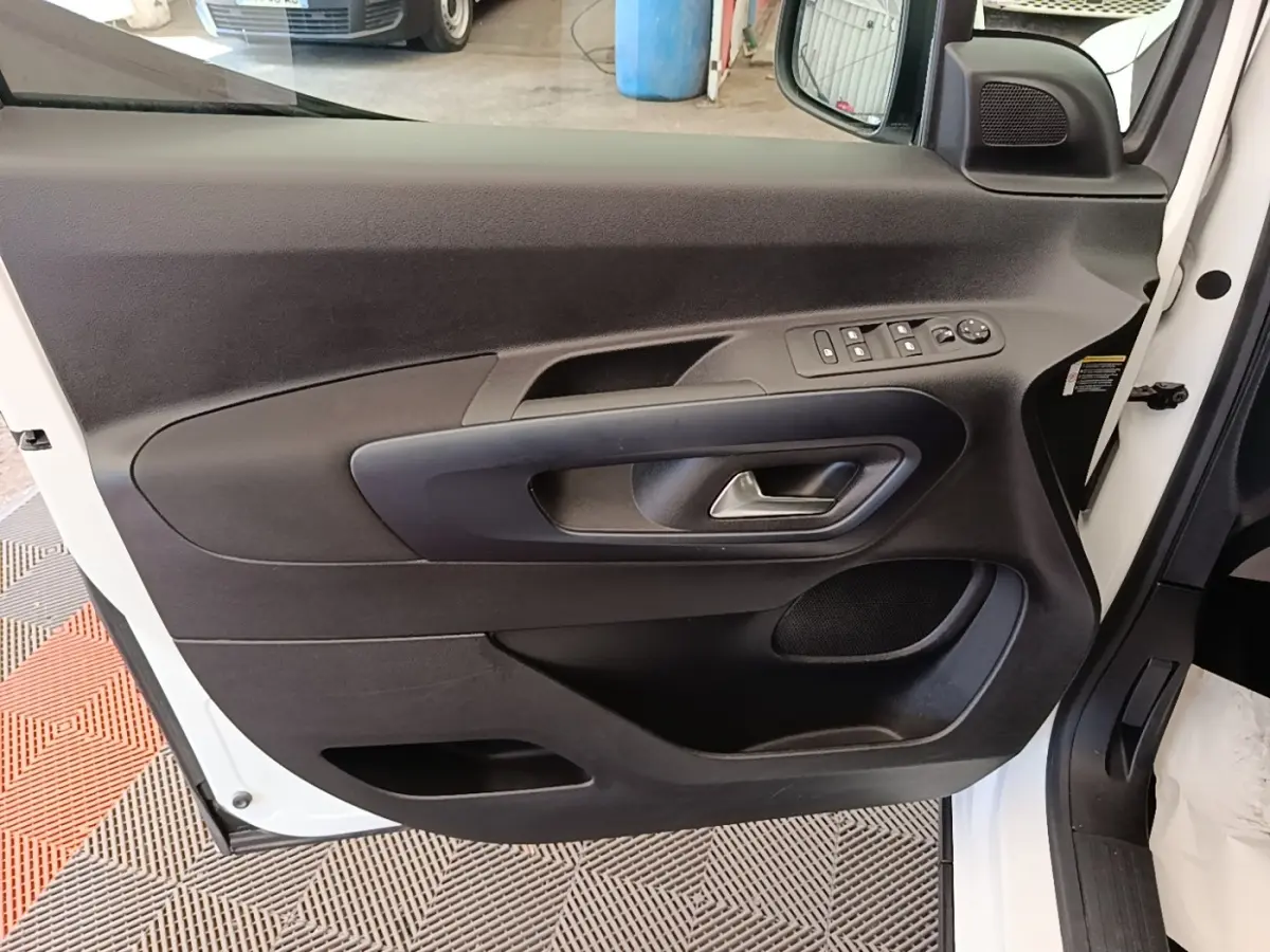 Vue rapprochée de la porte avant gauche blanche du Peugeot Rifter 2020, avec commandes électriques et poignée intégrée.