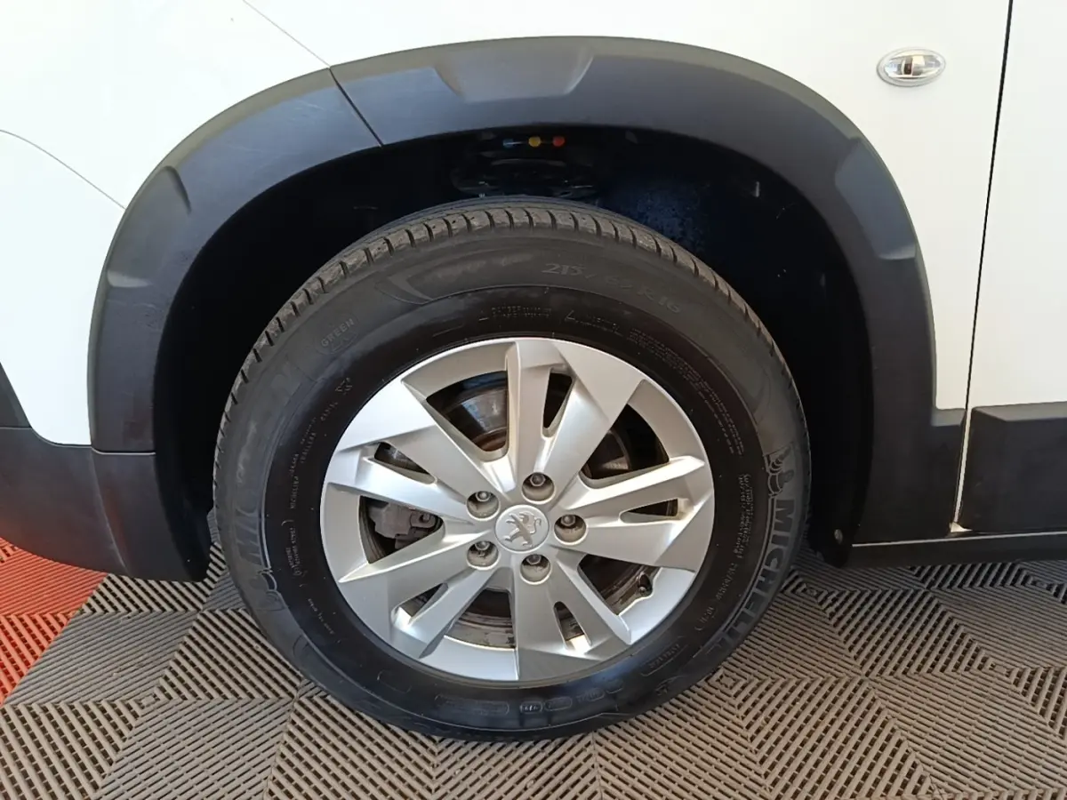 Gros plan sur la roue avant gauche du Peugeot Rifter blanc, avec jante alliage et pneu Michelin visible.