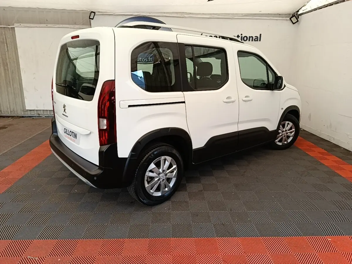 Vue 3/4 arrière droite d’un Peugeot Rifter blanc 2020 avec vitres teintées et jantes alliage.