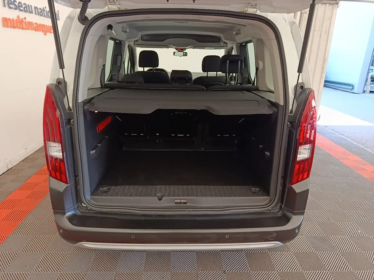 Vue arrière du coffre ouvert du Peugeot Rifter blanc 2020, montrant l'espace de chargement et la banquette arrière.