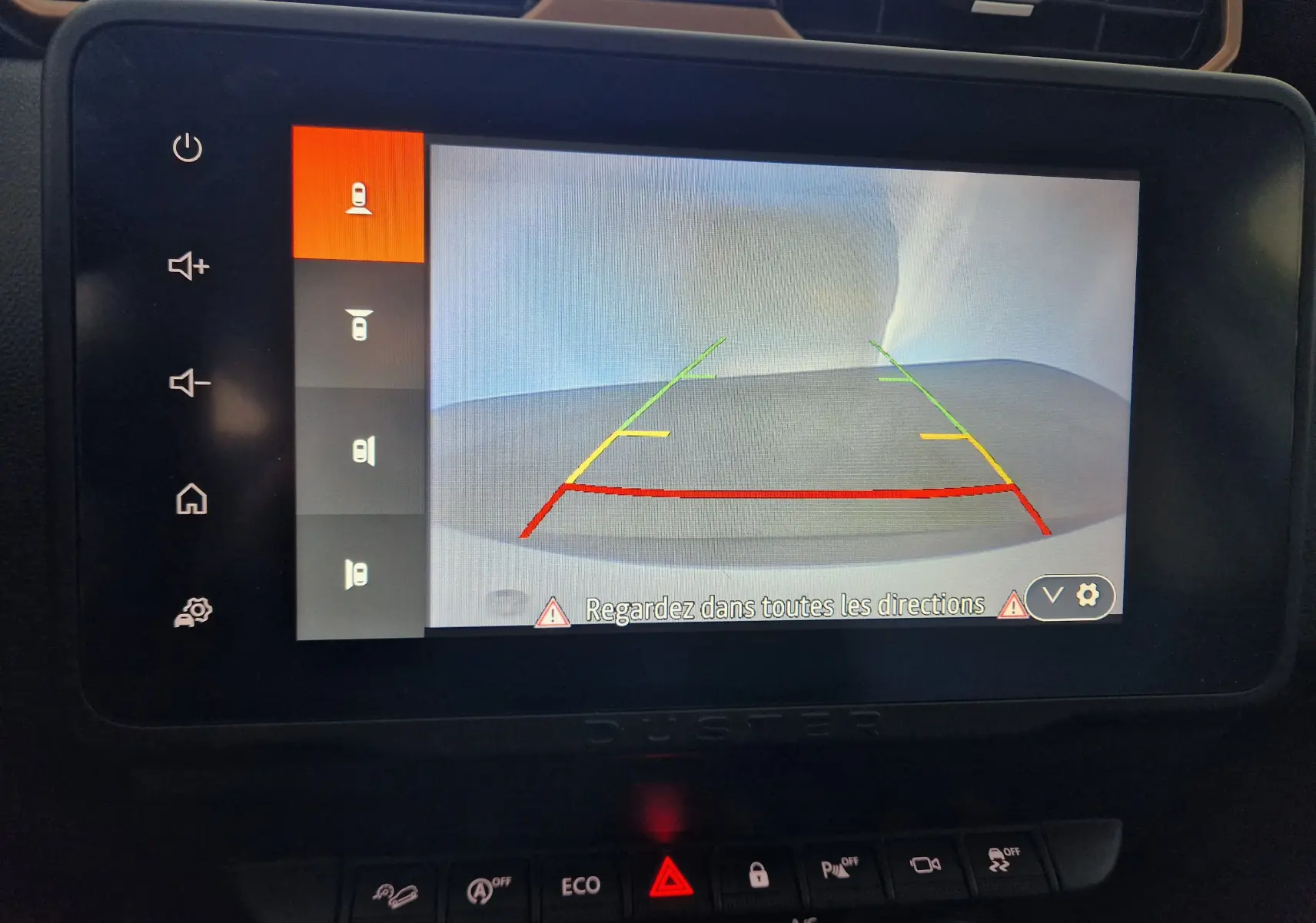 Écran central du Dacia Duster 2024 montrant la caméra de recul avec lignes de guidage colorées en intérieur noir.