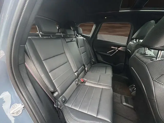 Banquette arrière en cuir noir Vernasca vue côté gauche du BMW X1 Storm Bay 2024 avec vitres surteintées et finitions M-Sport.