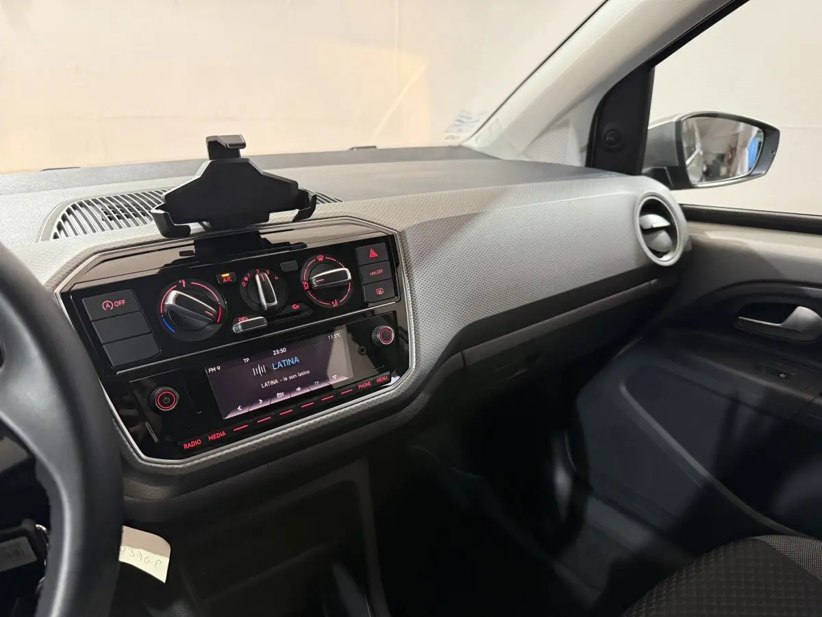 Intérieur de Volkswagen Up 1.0 65 Active 2022, vue côté passager sur tableau de bord et console centrale noire.