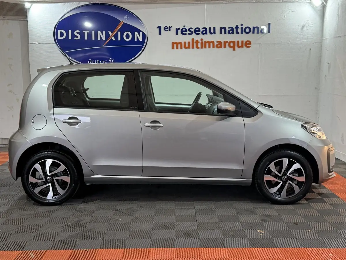 Profil côté gauche d'une Volkswagen Up gris foncé 2022, version 1.0 65 Active, en intérieur showroom.
