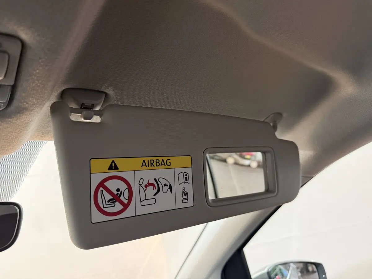 Détail du pare-soleil côté conducteur gris clair avec miroir et avertissement airbag dans un Volkswagen Up 2022.